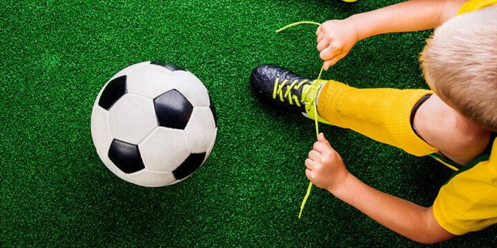 Person tying shoe next to soccer ball on field