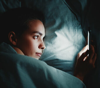 Person in bed lying awake and looking at phone