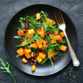 Salad topped with roasted squash and pomegranates