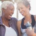Three women laughing outside in workout clothing
