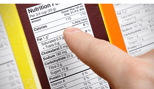 person looking at nutrition facts on box of food