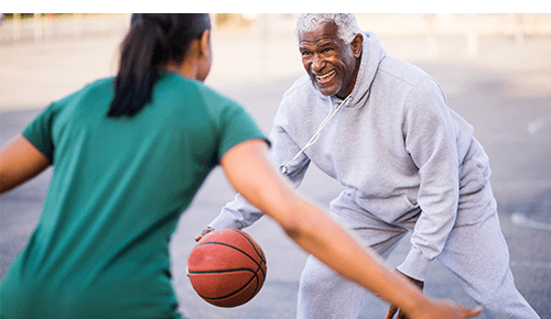 Man playing basketball with younger person