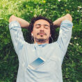 Man relaxing and listening to music on earbuds in grass