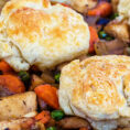 Biscuits sitting on top of chicken pot pie mixture in casserole dish