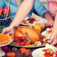 Person setting turkey down on a table full of Thanksgiving food