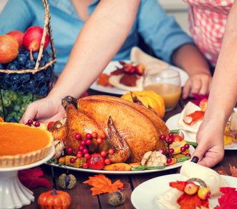 Person setting turkey down on a table full of Thanksgiving food