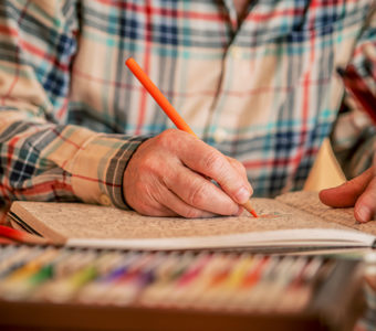 Person drawing in coloring book using colored pencils