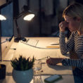 Person at desk in front of computer holding their head in their hand