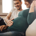 Couple smiling while man holds his hand on the woman's pregnant stomach