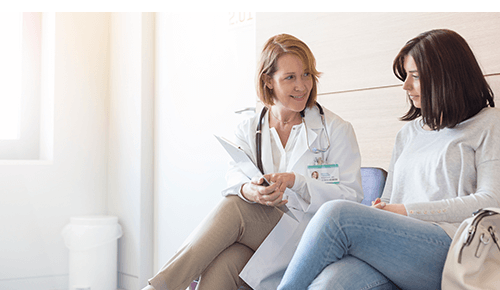 Doctor talking to woman and pointing to chart on clipboard