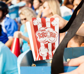 Person holding a container of popcorn in a sports stadium