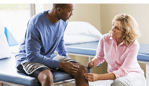 Doctor talking to patient seated on an exam table Doctor talking to patient seated on an exam table