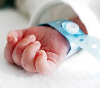 Newborn baby's hand with hospital bracelet on wrist