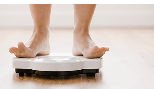 Person's feet standing on scale to weigh themself