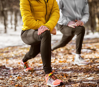 Two people stretching their legs outside before exercising
