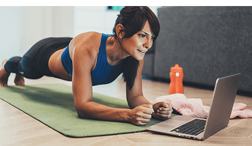 Person performing planks during exercise while looking at laptop