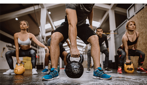 Group of people exercising using kettlebells in a gym