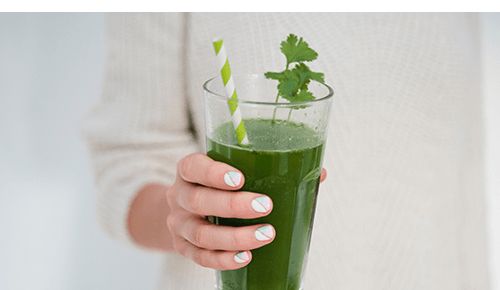 Person holding glass of green juice