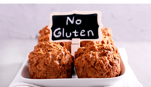 Plate full of muffins with sign that says No Gluten
