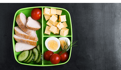 Lunchbox container with lean protein, cheese and slices of vegetable