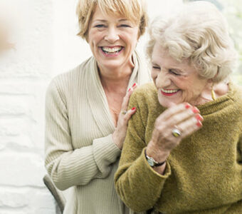 Middle-aged woman hugging older woman, both smiling