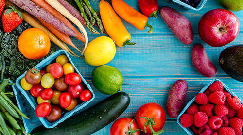 Variety of fruits and vegetables sitting on blue background