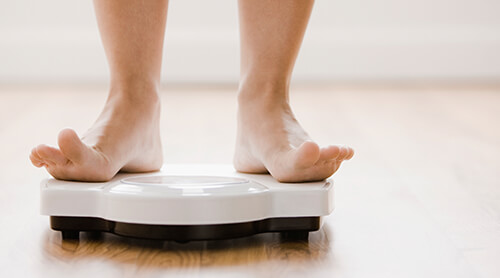 Person weighing themself on scale