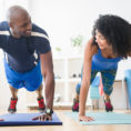 Two people working out and performing planks on a yoga mat