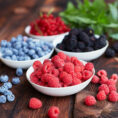 Bowls full of a variety of berries sitting on a wooden table