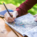 Person coloring in coloring book outdoors