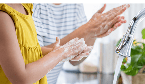 Adult and child washing hands together at sink