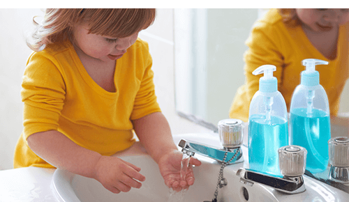 Young girl washing hands in sink