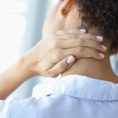 Person holding the back of their neck in pain