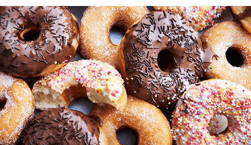 Closeup of a variety of donuts with chocolate, sprinkles and powdered sugar on top Closeup of a variety of donuts with chocolate, sprinkles and powdered sugar on top