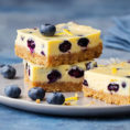 Squares of blueberry cheesecake sitting on a plate