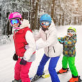 Three children holding on to each while skiing down a snow covered mountain