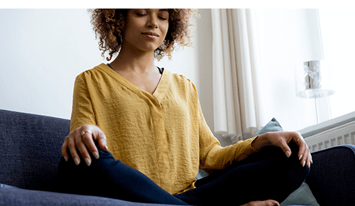 Woman practicing meditation on couch