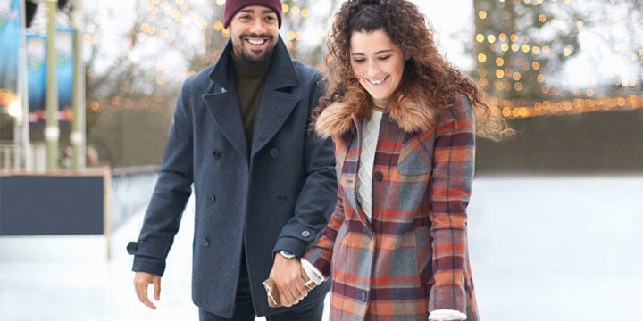 Couple holding hands while ice skating outdoors in the winter