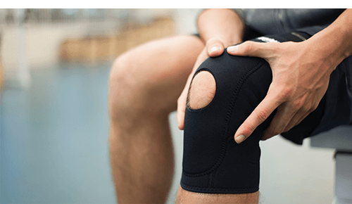 Person holding knee with brace on it Person holding knee with brace on it