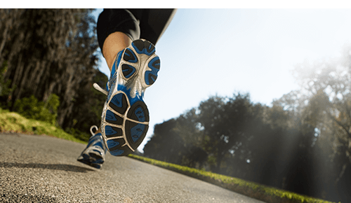 Closeup of someone running on a concrete path outdoors Closeup of someone running on a concrete path outdoors