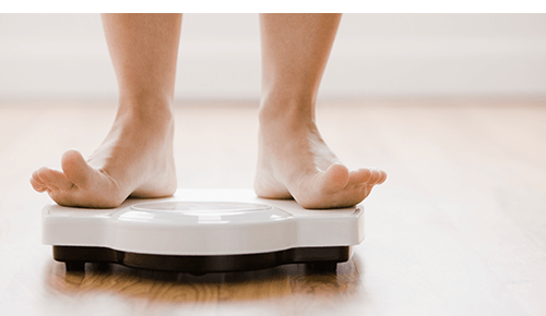 Person weighing themself on scale