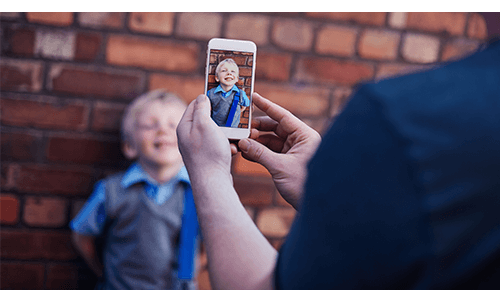 Person taking a picture of a child with their smart phone Person taking a picture of a child with their smart phone