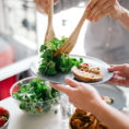 Person serving salad to dining companion