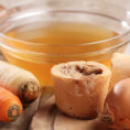 Bowl of bone broth surrounded by vegetables