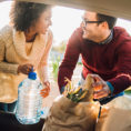 Couple loading groceries in bags into the back of a car