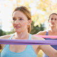 Two women using exercise bands while working out outdoors