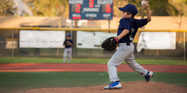 Child throwing a baseball from the pitcher's mound on a baseball field