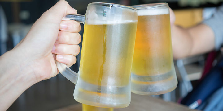Two people toasting with glass steins full of beer