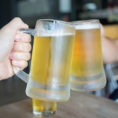 Two people toasting with glass steins full of beer