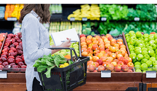 Person holding shopping basket looking at fruit in a grocery store
